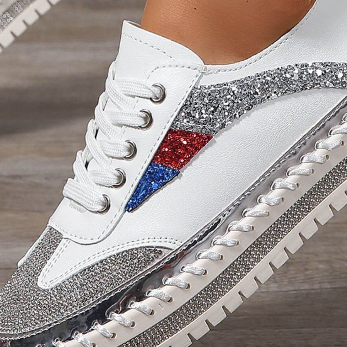 Close-up of stylish rhinestone sneakers with white base and colorful glitter detailing on the side.