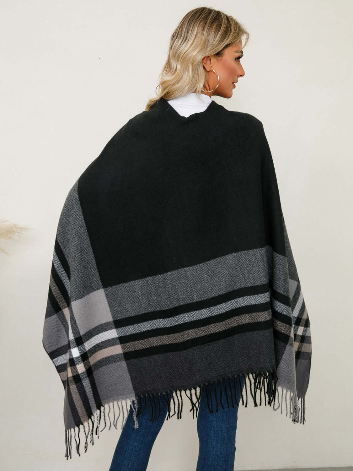 Stylish woman wearing a Fringe Contrast Plaid Poncho with fringe detail, perfect for cozy fall outings.