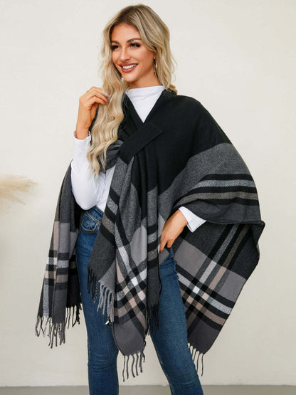 Stylish woman in a black and gray Fringe Contrast Plaid Poncho, radiating cozy vibes and chic elegance.