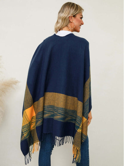 Cozy woman wearing a Fringe Contrast Plaid Poncho with chic fringe and bold colors, perfect for stylish layering.