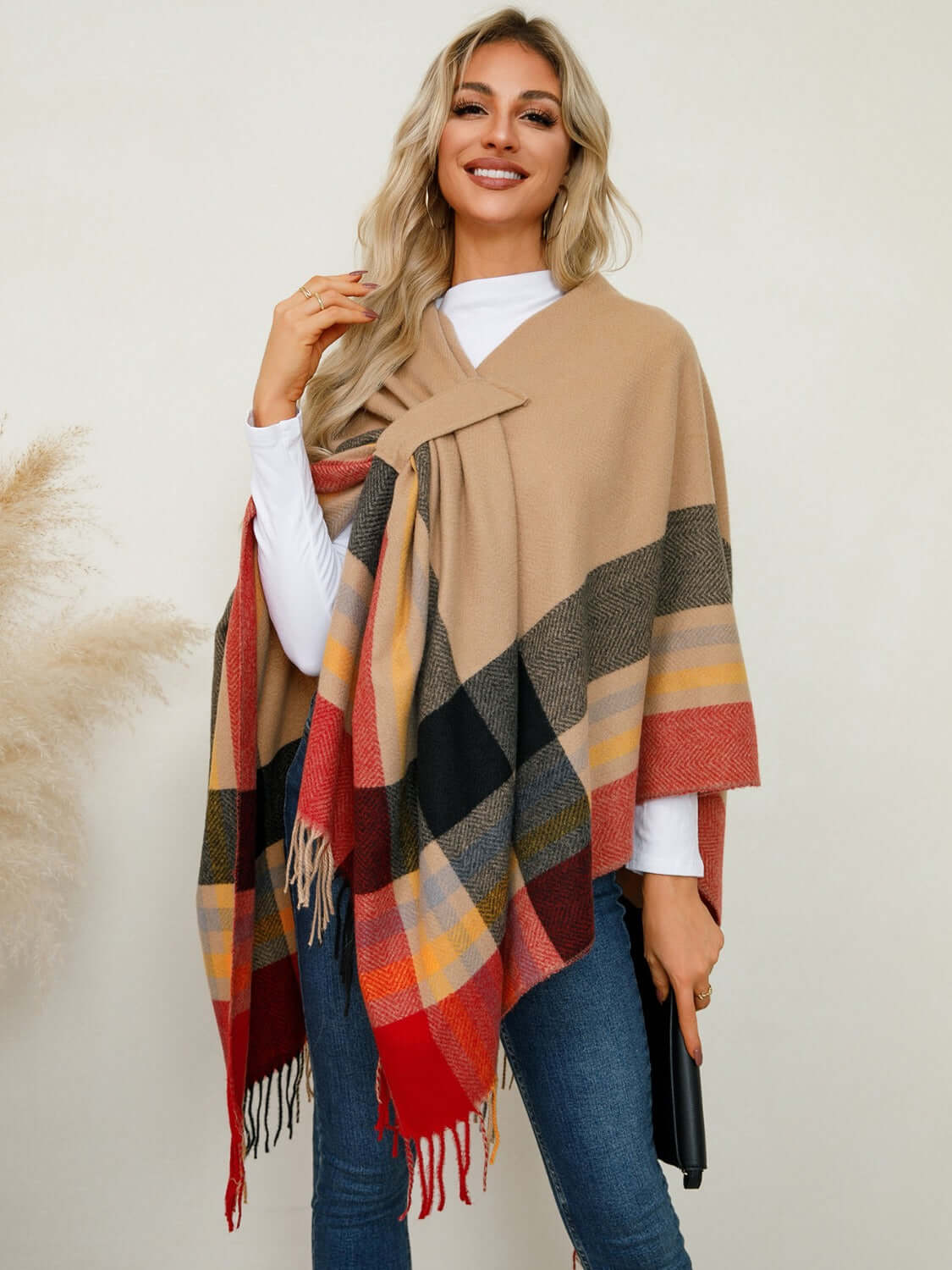 Stylish woman wearing a Fringe Contrast Plaid Poncho with chic fringe detail and bold plaid design. Perfect for cozy vibes!